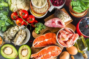 Pescetarian diet plan ingredients, healthy balanced grocery food, fresh fruit, berries, fish and shellfish clams, black stone concrete background copy space