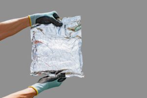 A worker in gloves is holding a packaging bag made of a material with foil