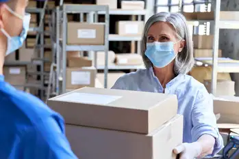 A delivery worker handing secure, temperature-controlled packages to a clinic staff member, highlighting safe last-mile logistics for specialty medicine.