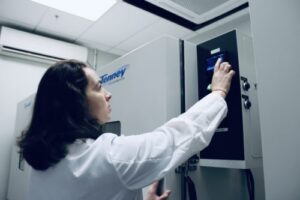 Laboratory scientist using a touchscreen panel to configure an environmental test chamber for medical storage.
