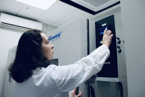 Laboratory scientist using a touchscreen panel to configure an environmental test chamber for medical storage.